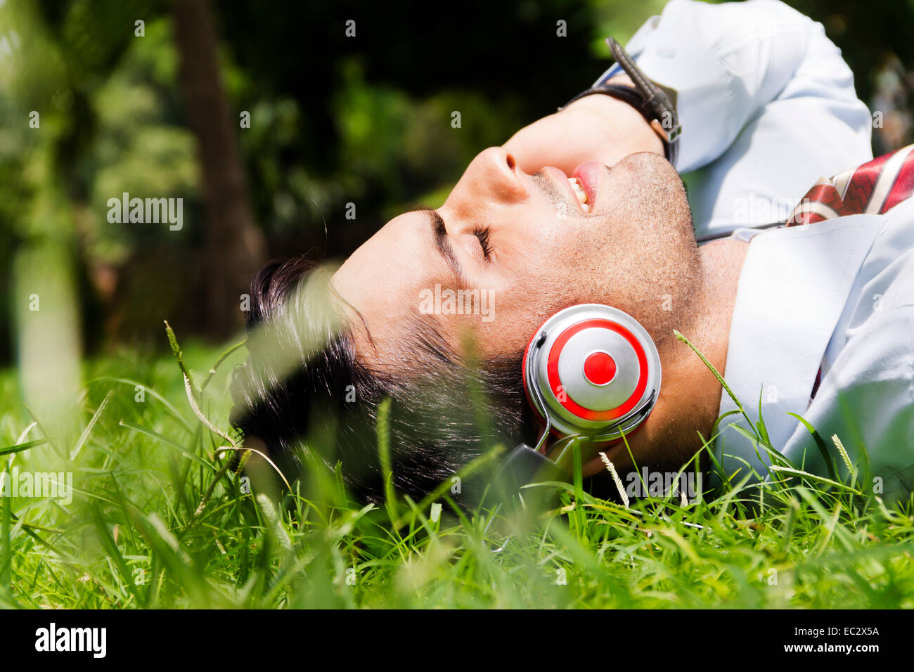 indische Geschäftsmann Park hören von Musik Stockfoto