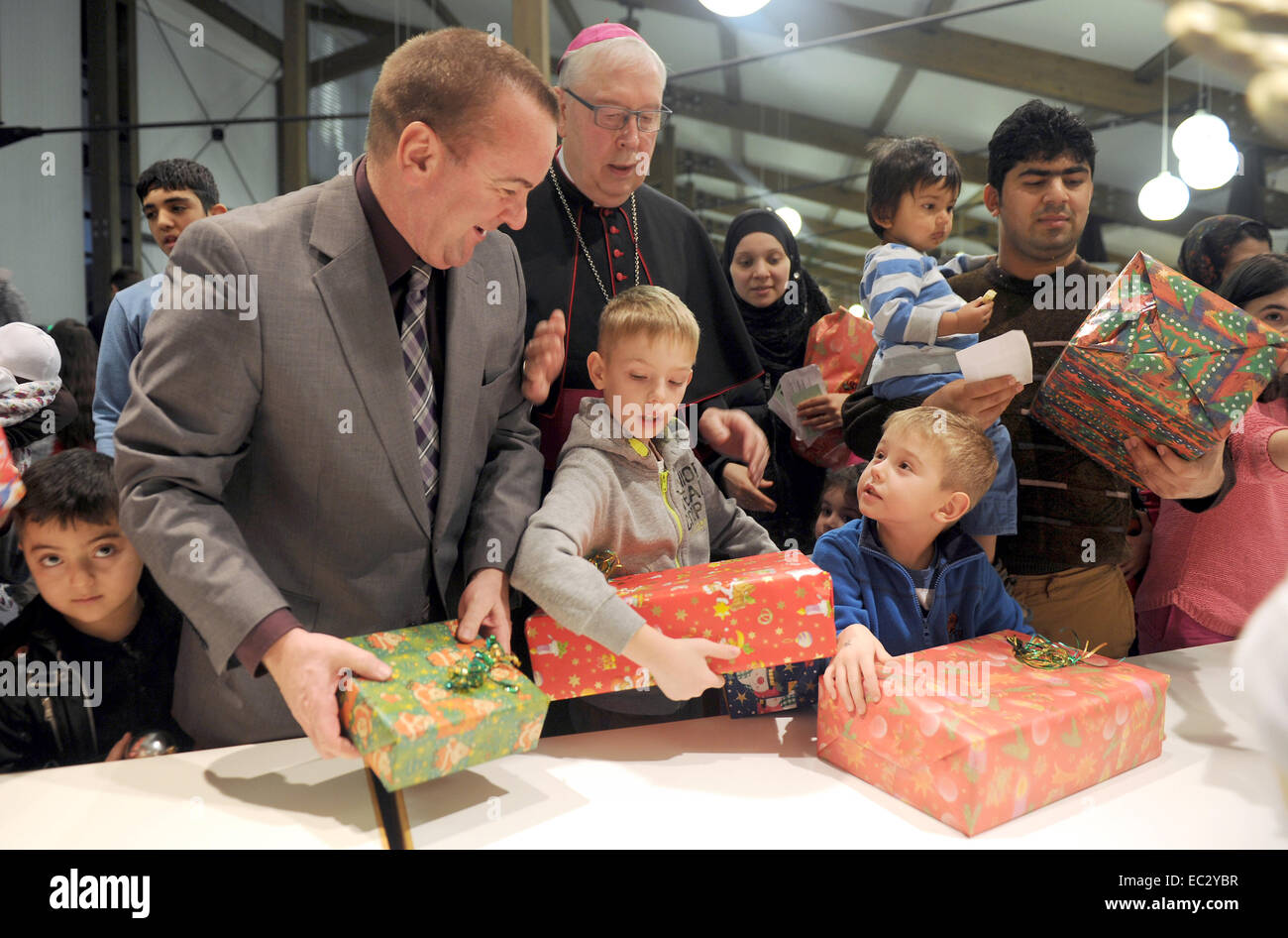 Datei - Datei Bild datiert 16. Dezember 2013 zeigt die Innenminister der unteren Sachsen Boris Pistorius (SPD, L) und Bischof des Bistums Hildesheim Norbert Treller (2-L), die während der Weihnachtsfeier im Lager Friedland für Asylbewerber und ethnischen deutschen Emigranten Geschenke verteilen. Das diesjährige Weihnachtsfeier im Camp wird am 9. Dezember 2014 stattfinden. Foto: Swen Pfoertner/dpa Stockfoto