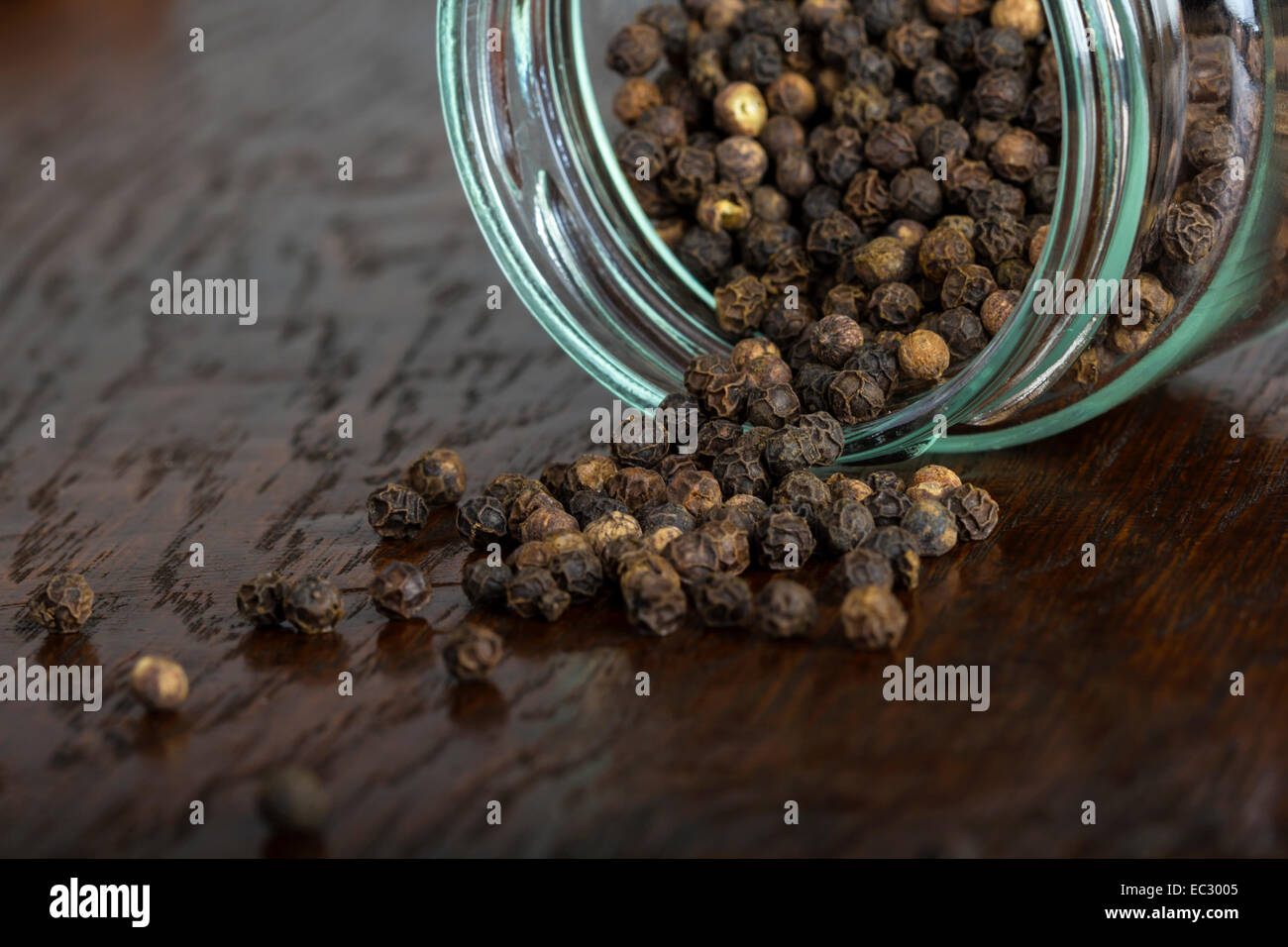 Nahaufnahme von Pfeffer Samen aus einem Glas auf einem hölzernen Hintergrund Stockfoto