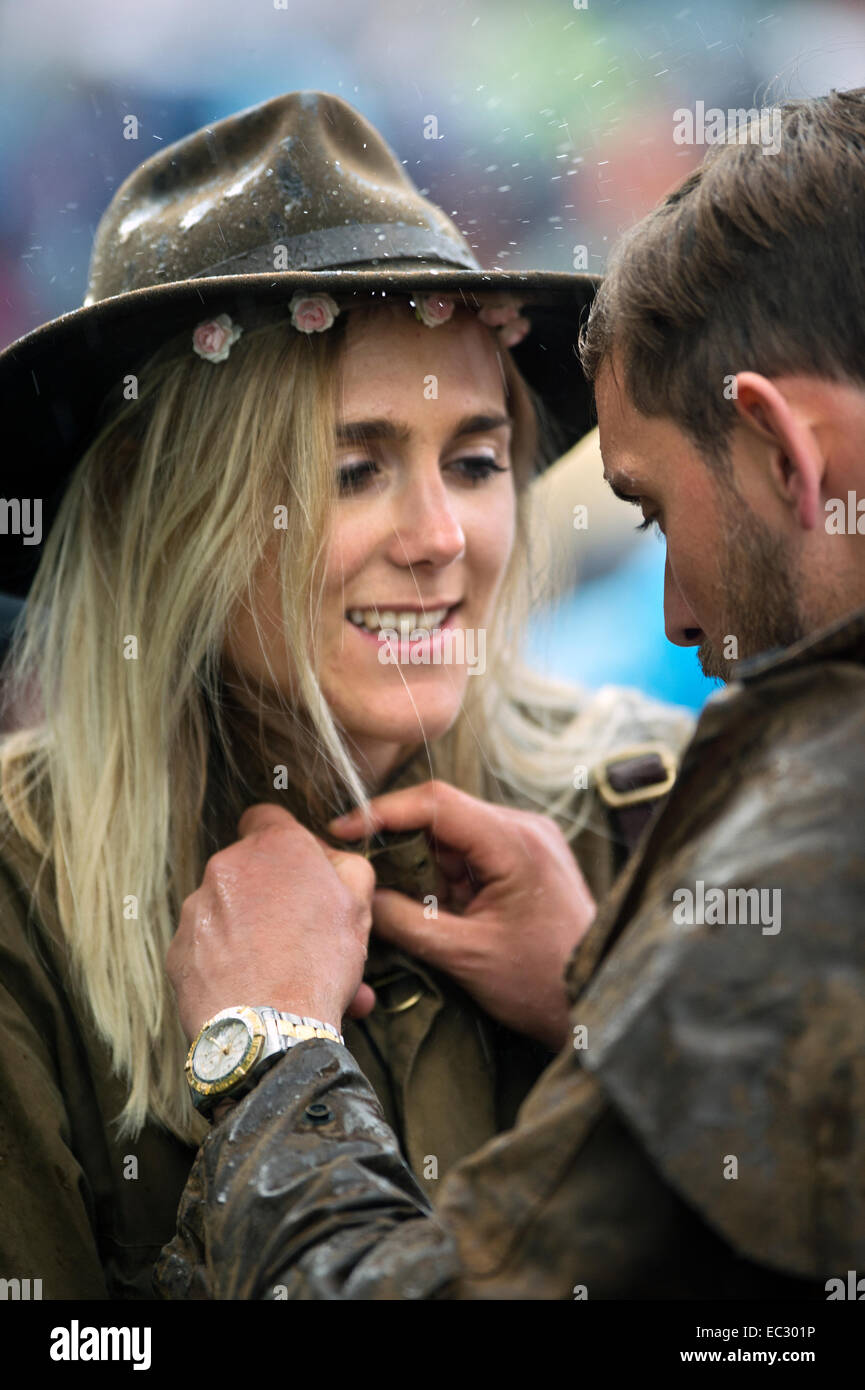 Ein paar in Wachs-Jacken-Knopf gegen den Regen auf dem Glastonbury Festival 2014 Stockfoto