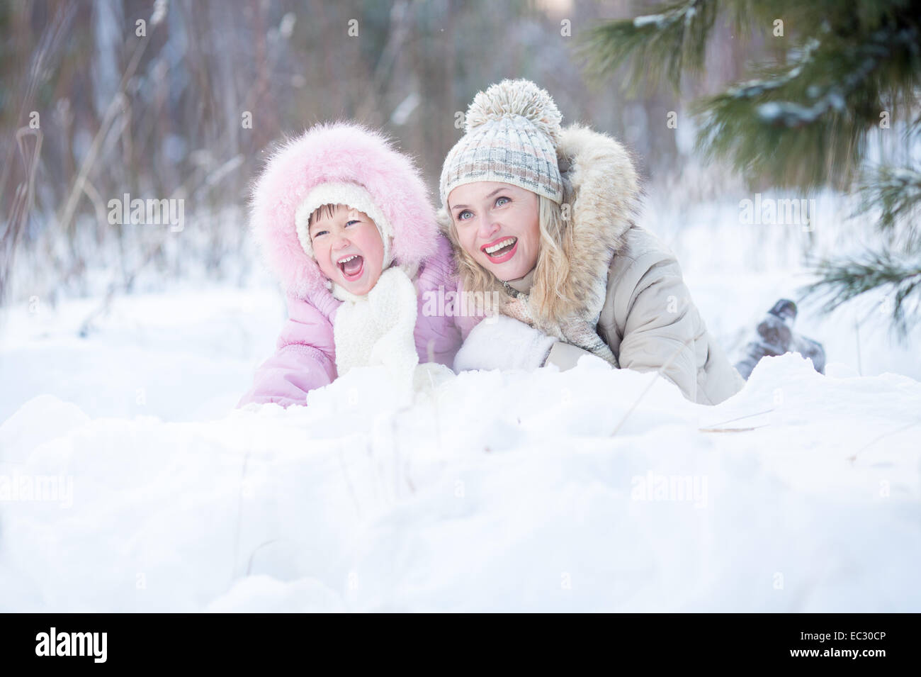 Glückliche Mutter und Kind im Schnee im freien liegend Stockfoto