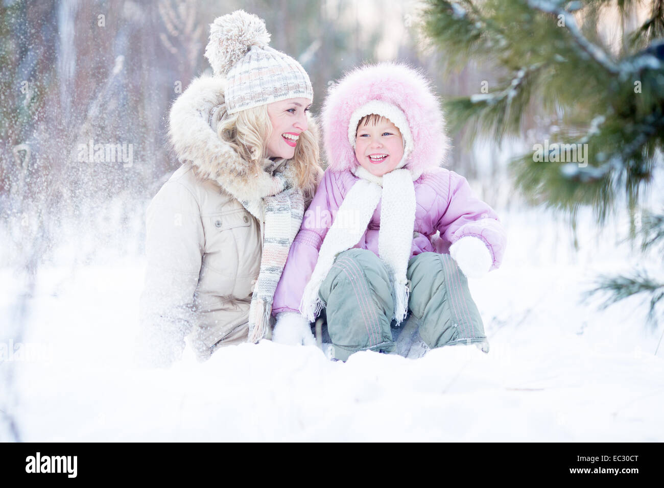 Glückliche Familie sitzen im Schnee im Winter Stockfoto
