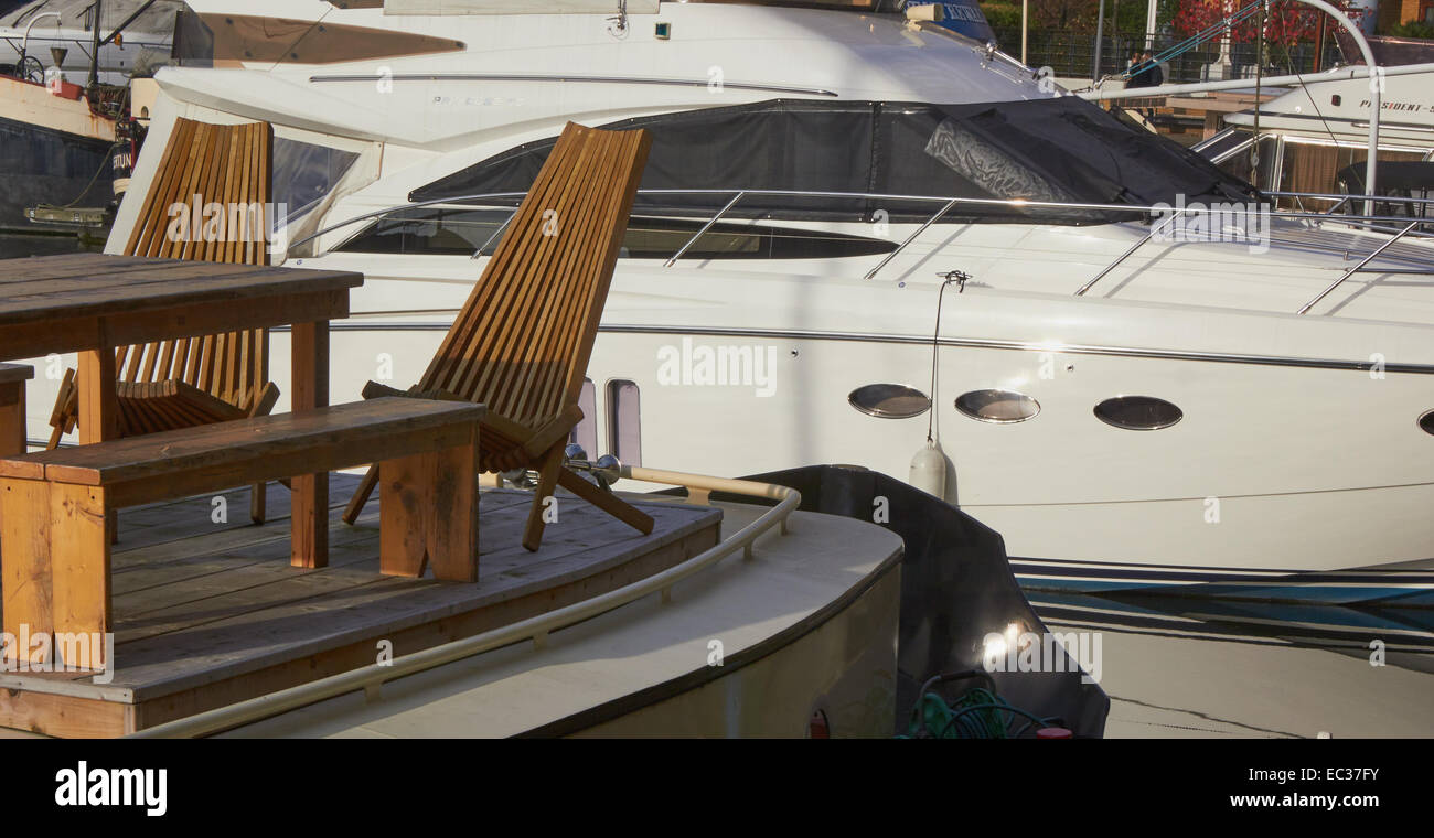 Stilvolle Stühle aus Holz auf dem Deck der Luxus Yacht mit Schnellboot hinter St. Katherine Docks marina London England Europa Stockfoto