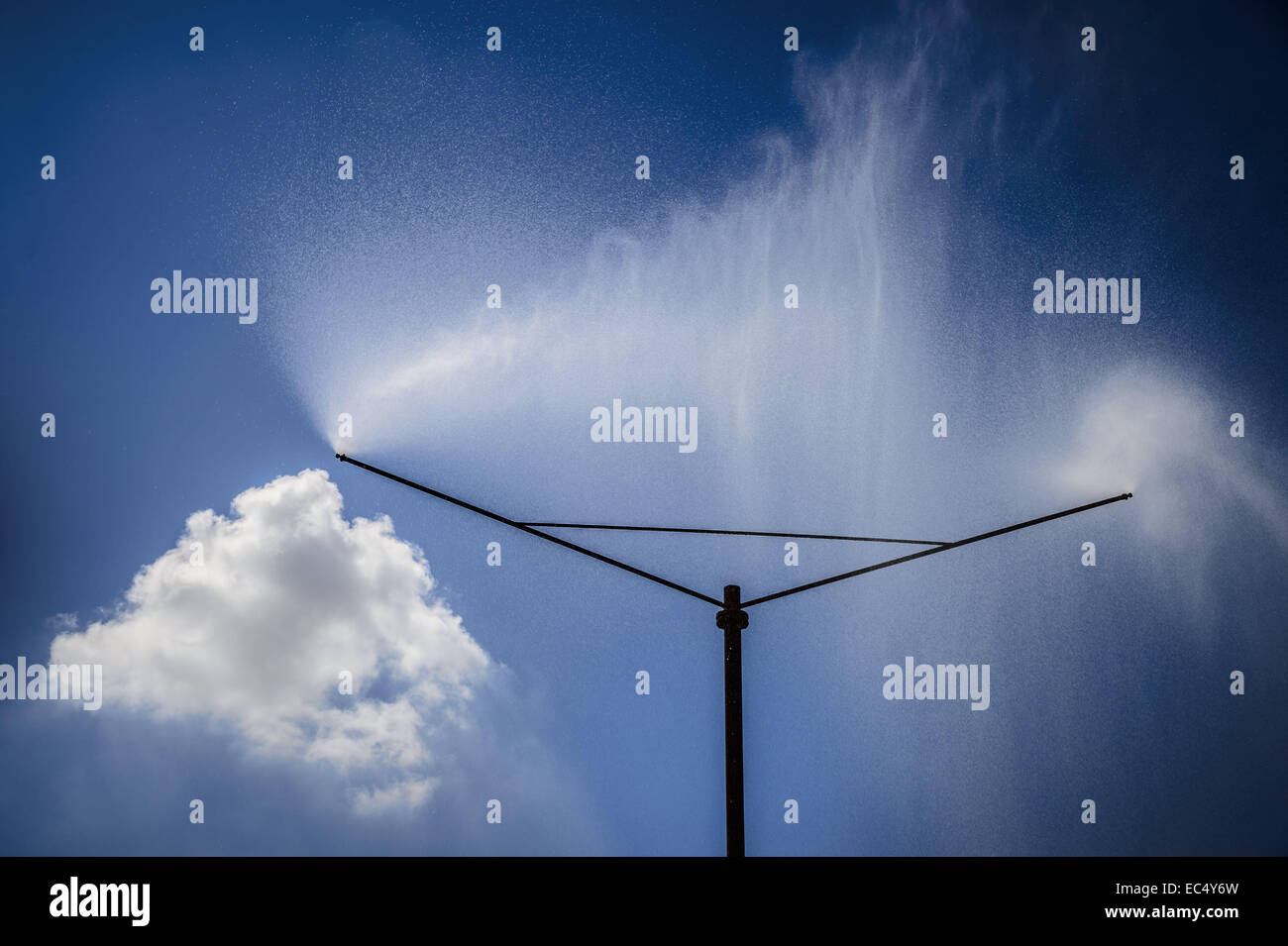 Eine Sprinkleranlage sprüht einen Wasservorhang gegen blauen Himmel Stockfoto