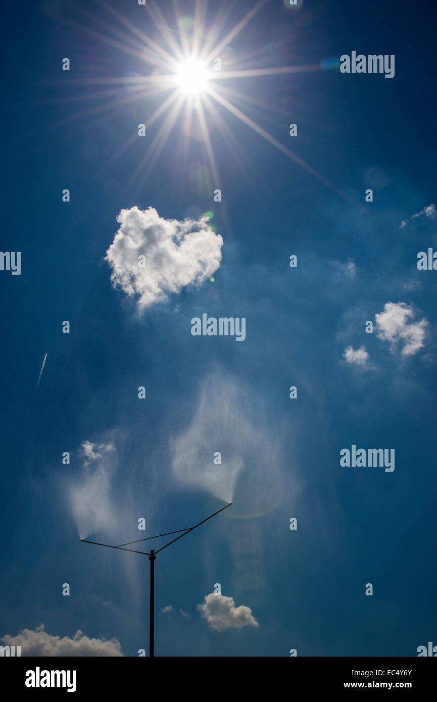 Eine Sprinkleranlage sprüht einen Wasservorhang gegen blauen Himmel Stockfoto