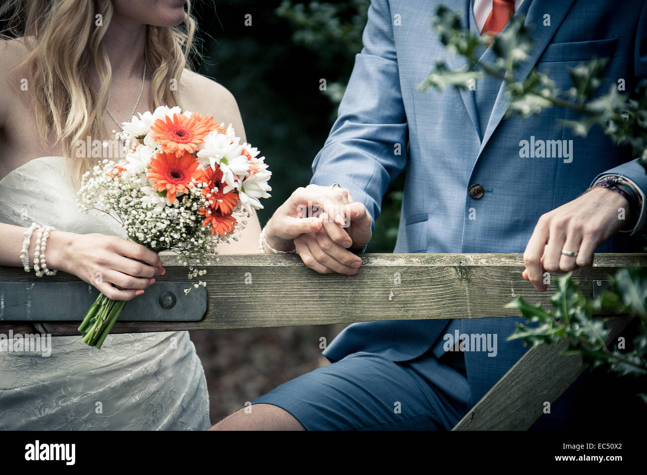 Braut und Bräutigam hinter Land Tor am Vintage Dorfhochzeit mit hausgemachten Brautstrauß und Bräutigam in kurzen Hosen, D.I.Y Hochzeit Stockfoto