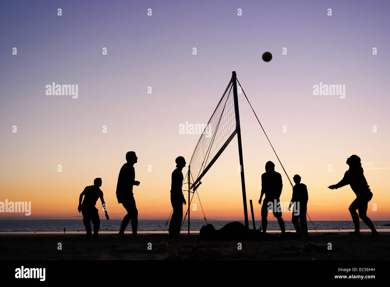 Silhouetten von einer Gruppe junger Menschen spielen Beach-Volleyball am Strand in der Bretagne, Frankreich Stockfoto