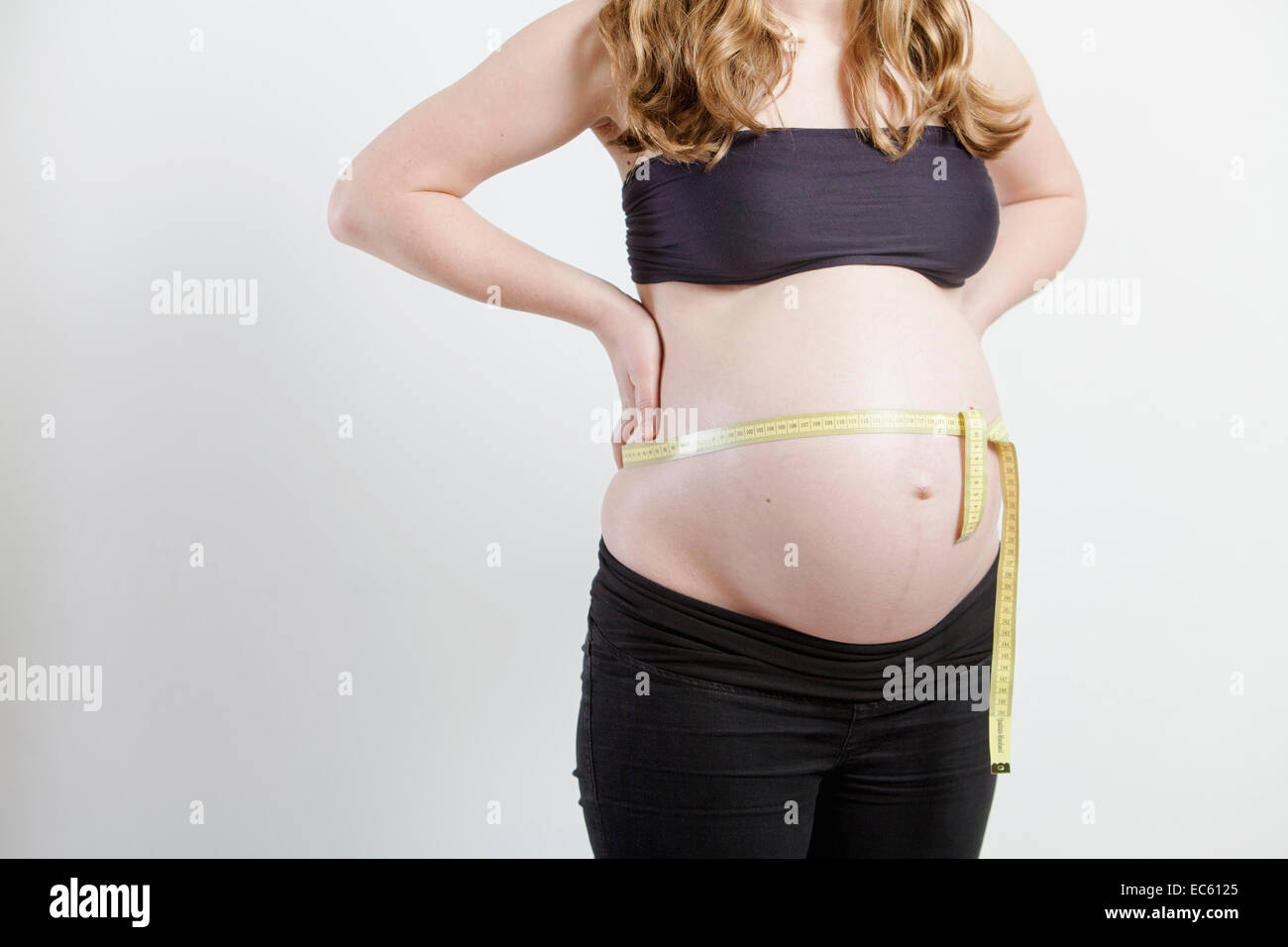 junge schwangere Frau mit einem Maßband um Ihren Bauch, Babybauch, Messen,  body, Größe, Umfang, Größe, werdende Mutter Stockfotografie - Alamy