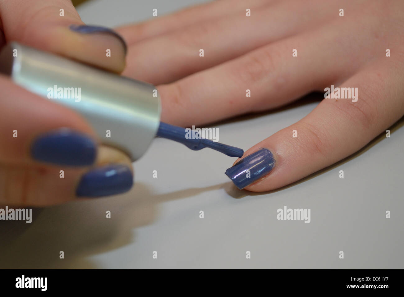 Teenager malt ihre Fingernägel blau Stockfoto