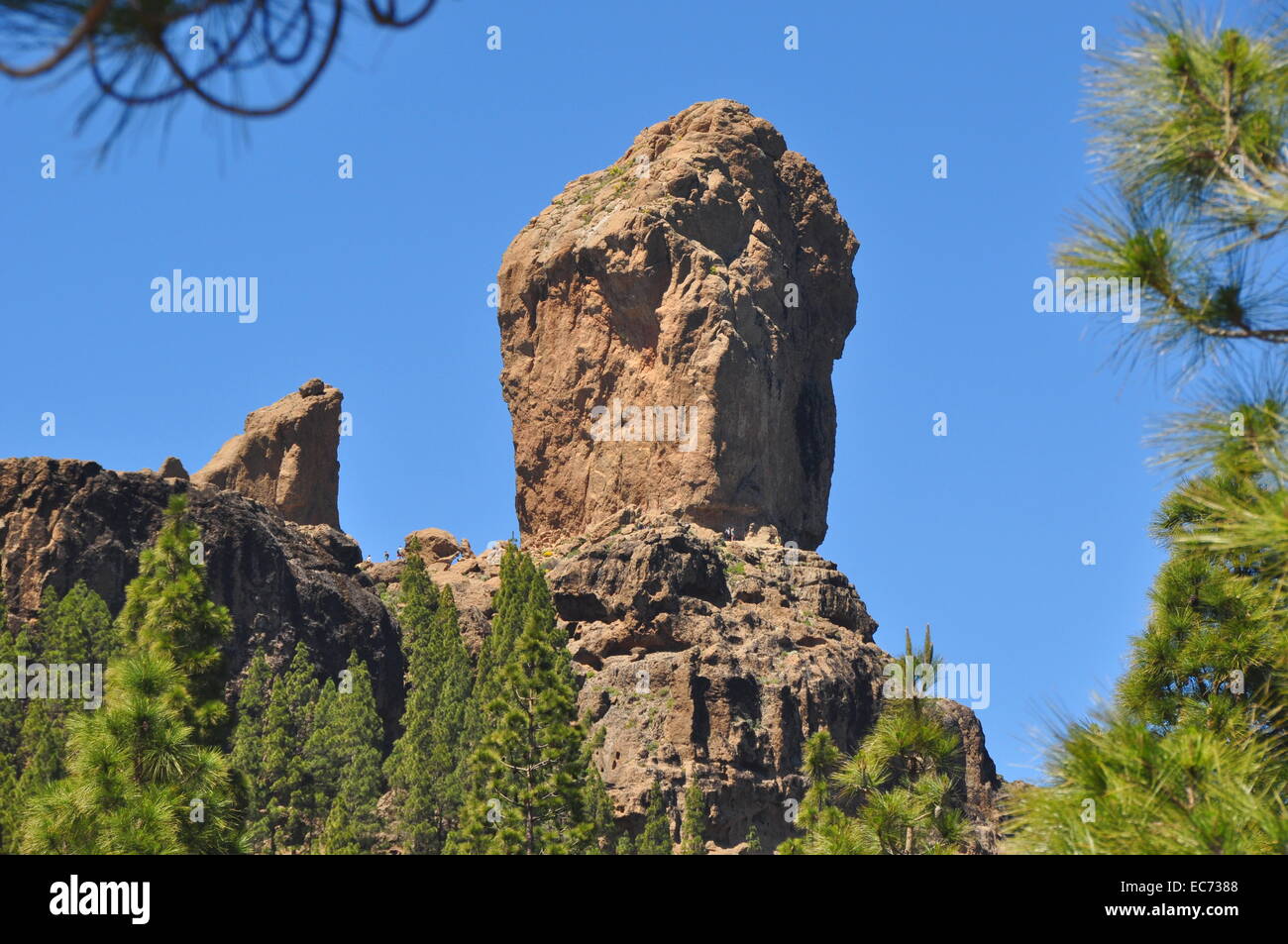 Roque Nublo aus Distanz betrachtet. Kleine Leute zu Fuß unter dem Felsen. Stockfoto