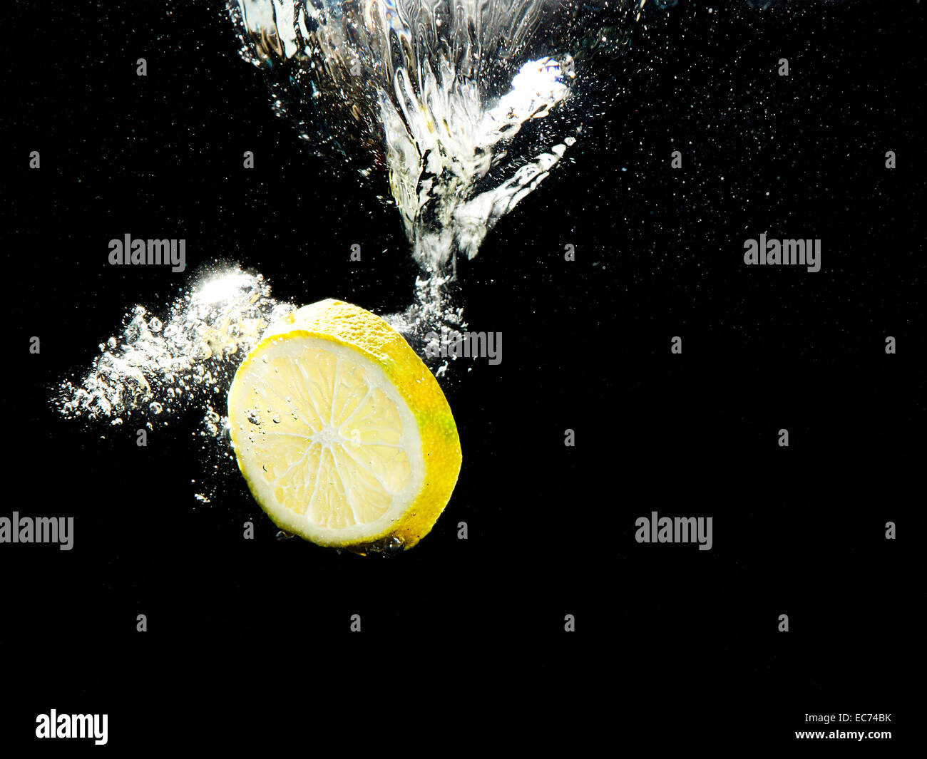 Zitronenscheibe ins Wasser plantschen. Stockfoto