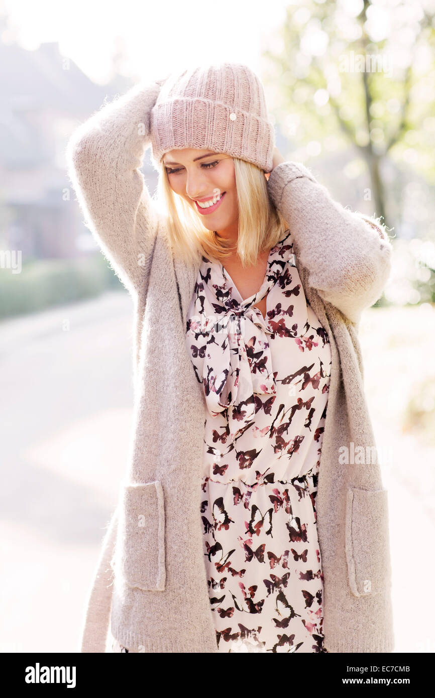 Lächelnde blonde Frau gemusterten Kleid, Mütze, Strickjacke und Wolle  Stockfotografie - Alamy