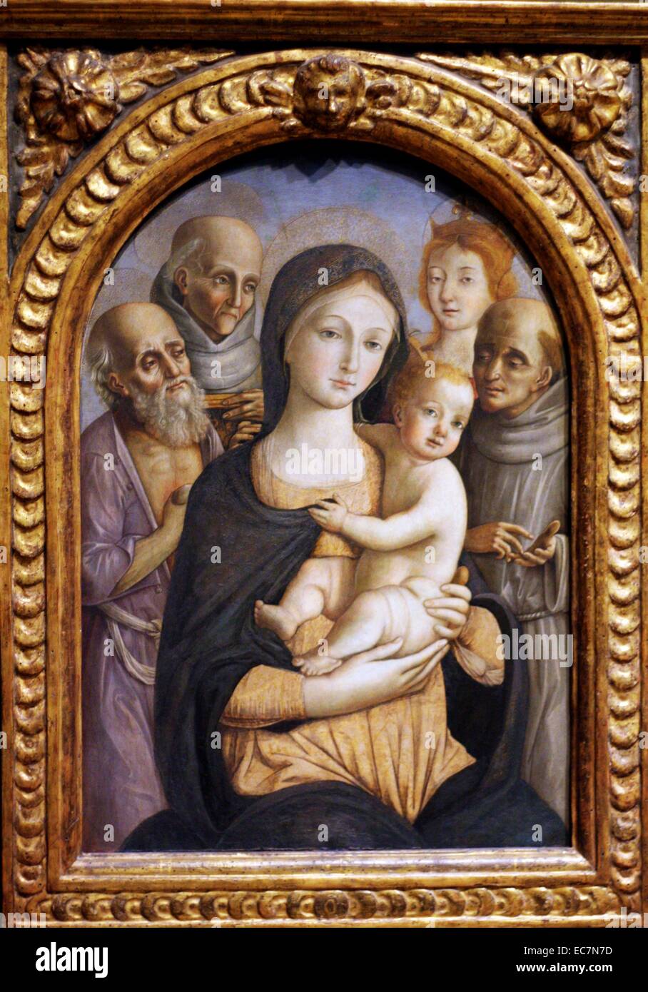Pietro Orioli (1458-1496) Die Jungfrau und Kind mit vier Heiligen. Tempera und Gold auf. Orioli wurde für seine Frömmigkeit sowie für seine Kunst. Er hoch heiligen Bilder gemalt raffinierte bekannt. Dieses Design erinnert an frühere Traditionen im sienesischen Kunst. Stockfoto