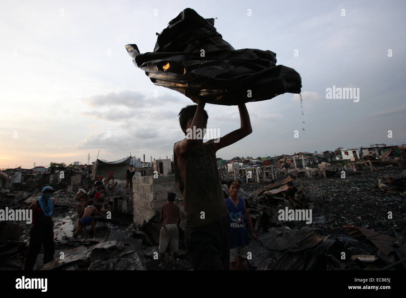 Malabon City, Philippinen. 10. Dezember 2014. Ein Bewohner sammelt wiederverwendbaren Materialien von verbrannten Häuser, nach ein Brand einem Slumviertel in Malabon Stadt, den Philippinen, 10. Dezember 2014 getroffen. Sechs Menschen wurden verletzt in das Feuer, die 200 Häuser und linken 400 Familien obdachlos dem Erdboden gleichgemacht. © Rouelle Umali/Xinhua/Alamy Live-Nachrichten Stockfoto