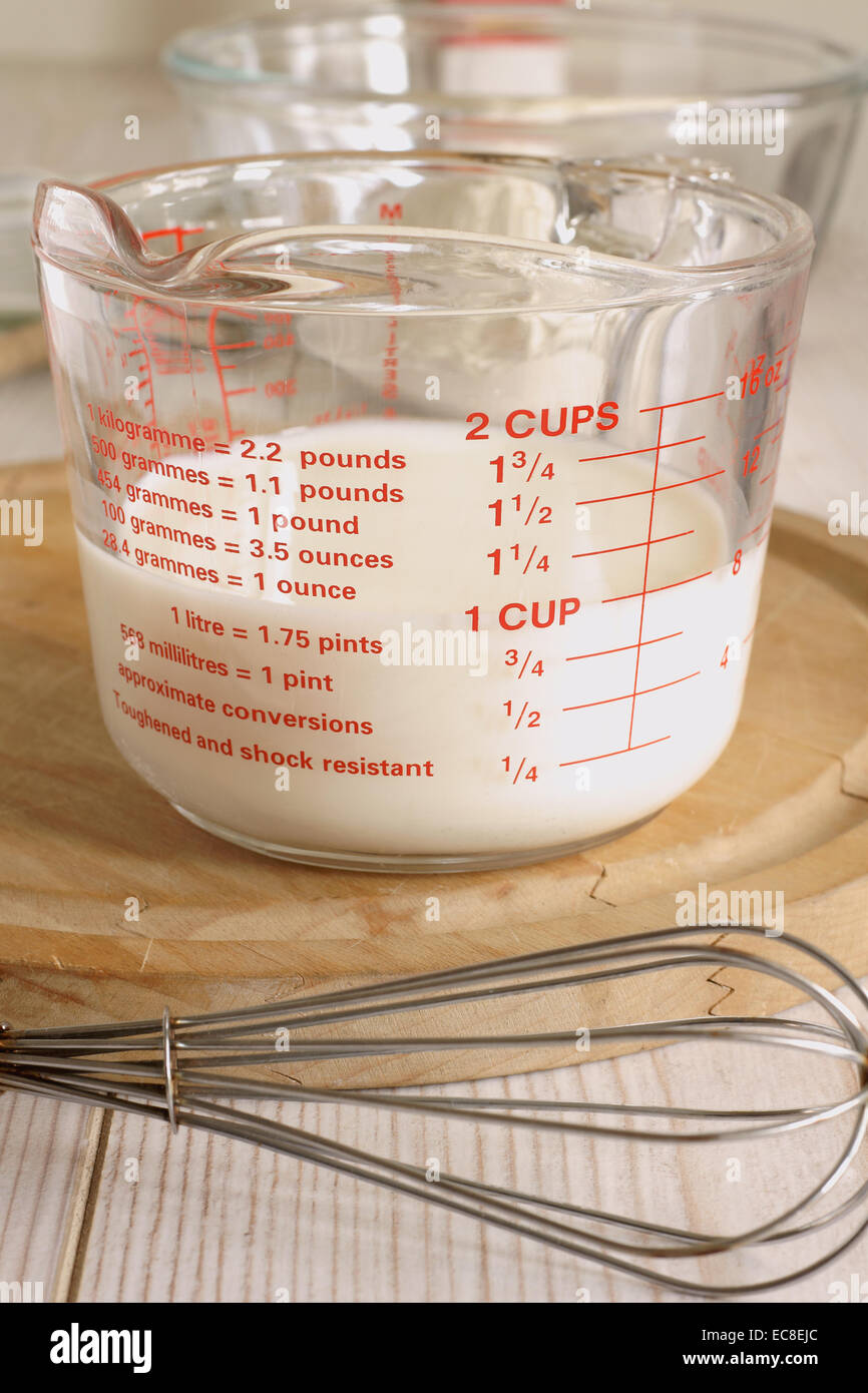 Messen Sie die Milch in einem Messgerät Krug zum Kochen oder Backen Stockfoto