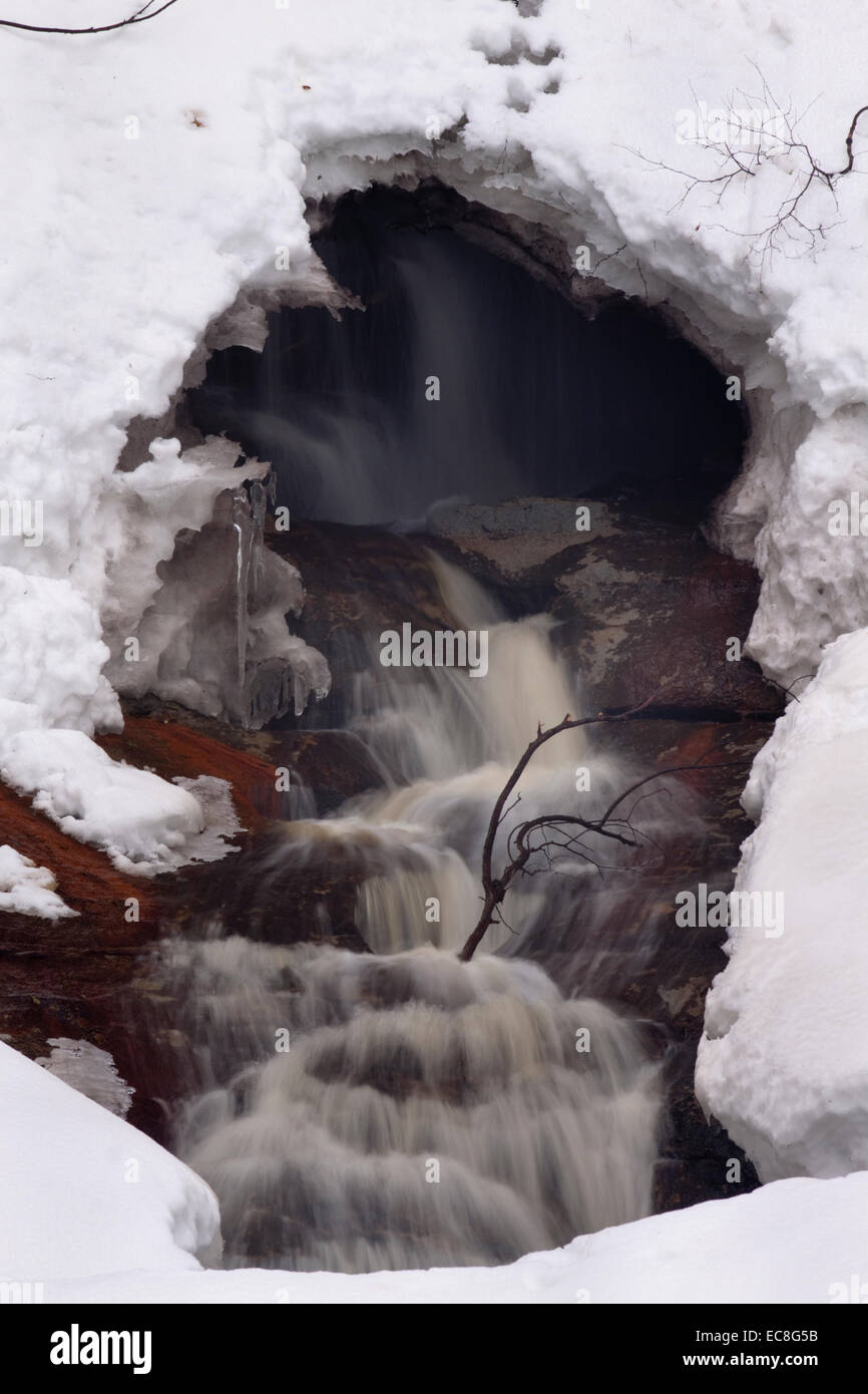 Flussabwärts der Munising Falls in der Upper Peninsula Michigan lag eine Öffnung in der Schneedecke und enthüllte einen versteckten Wasserfall im Inneren. Stockfoto