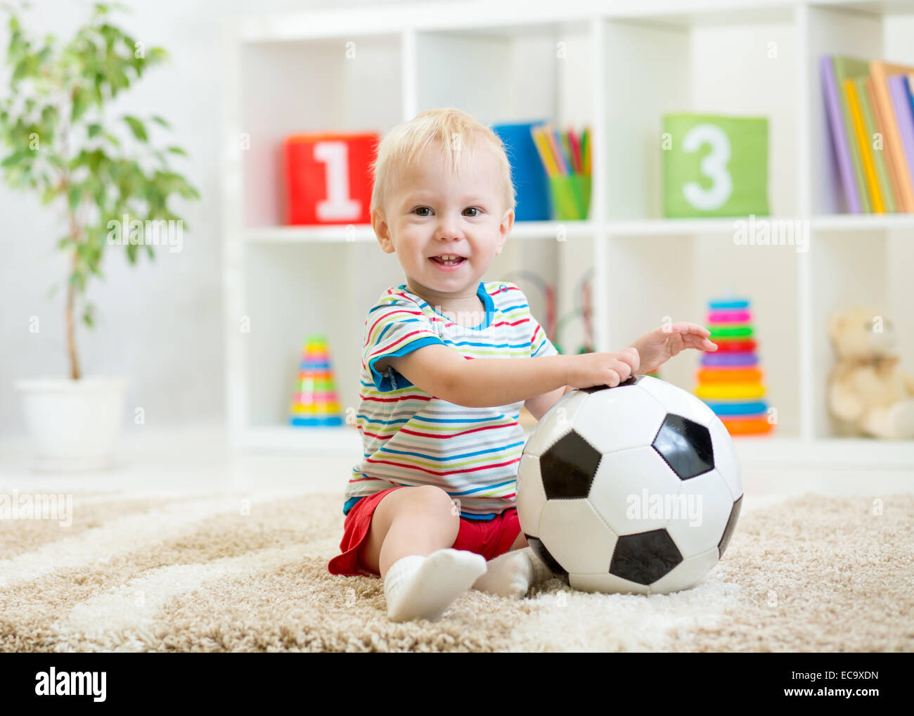 lächelndes Kind Junge mit Fußball indoor Stockfoto