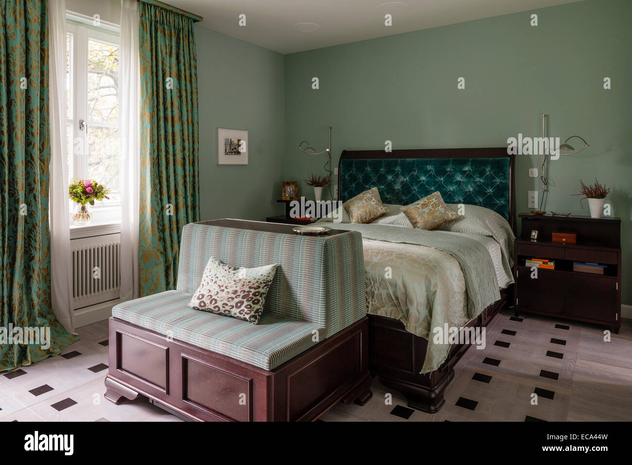 Aquamarin samt zugeknöpft Kopfteil auf Bett im Schlafzimmer mit Grün und gold print Vorhänge Stockfoto