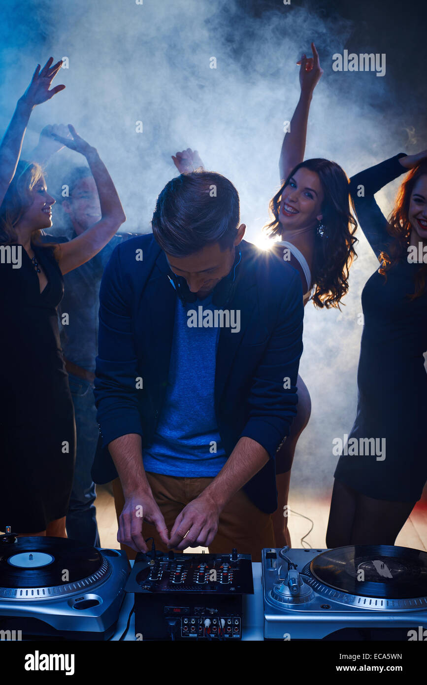 Glückliche Mädchen tanzen im Nachtclub während dj spielen energiegeladene Musik Stockfoto