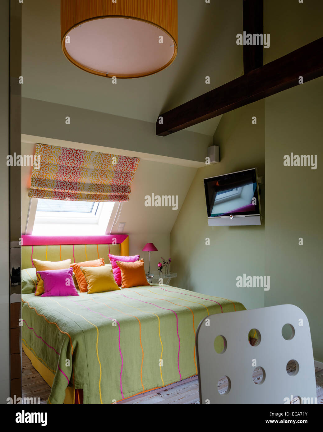 Hellen Kissen und gestreiften Wurf mit passenden Kopfteil auf Bett im Zimmer mit Dachfenster Stockfoto