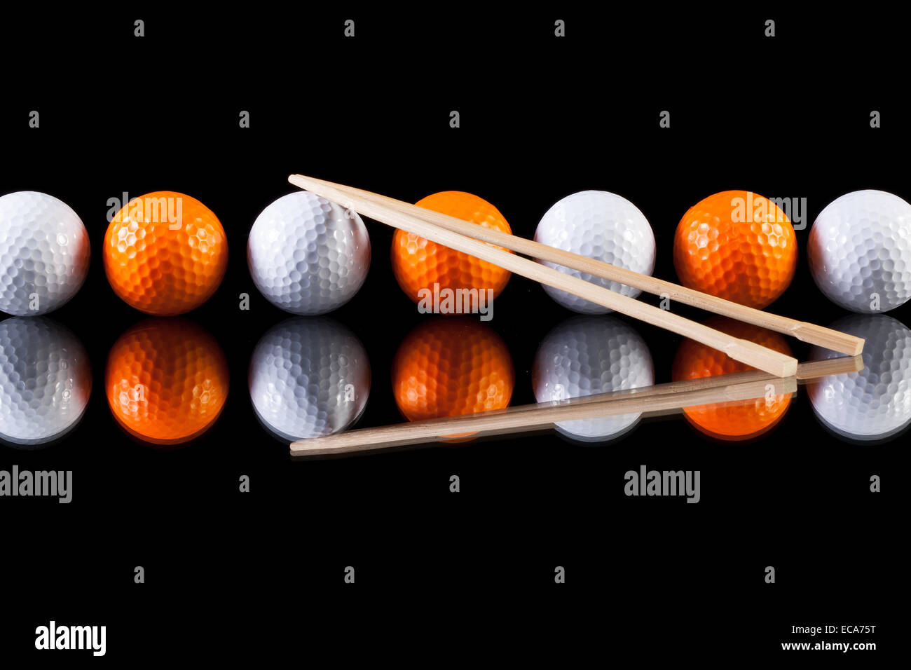 Weiß und orange Golfbälle mit Bambus Stäbchen auf dem Glastisch Stockfoto