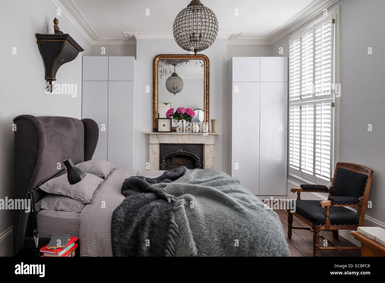 Luxus gepolsterten Bett vom Bridgepoint im Schlafzimmer mit Kamin, eingebauten Speicher und Schuld gerahmten Spiegel. Stockfoto