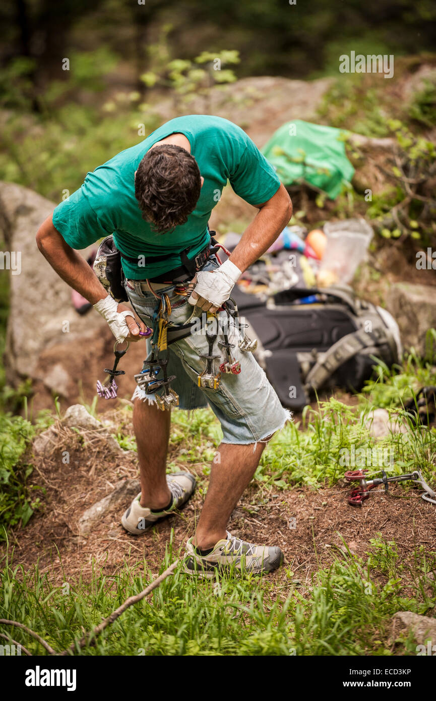 Italienischer Bergsteiger sein Gurtzeug während der Vorbereitung für den Aufstieg einer harte Riss Route einige Kletterausrüstung (Freunde und Nüssen) zuweisen. Esigo, Italien. Stockfoto