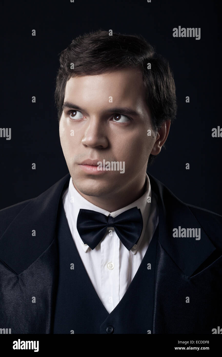 Porträt des jungen Mann im Smoking auf dunklem Hintergrund isoliert Stockfoto