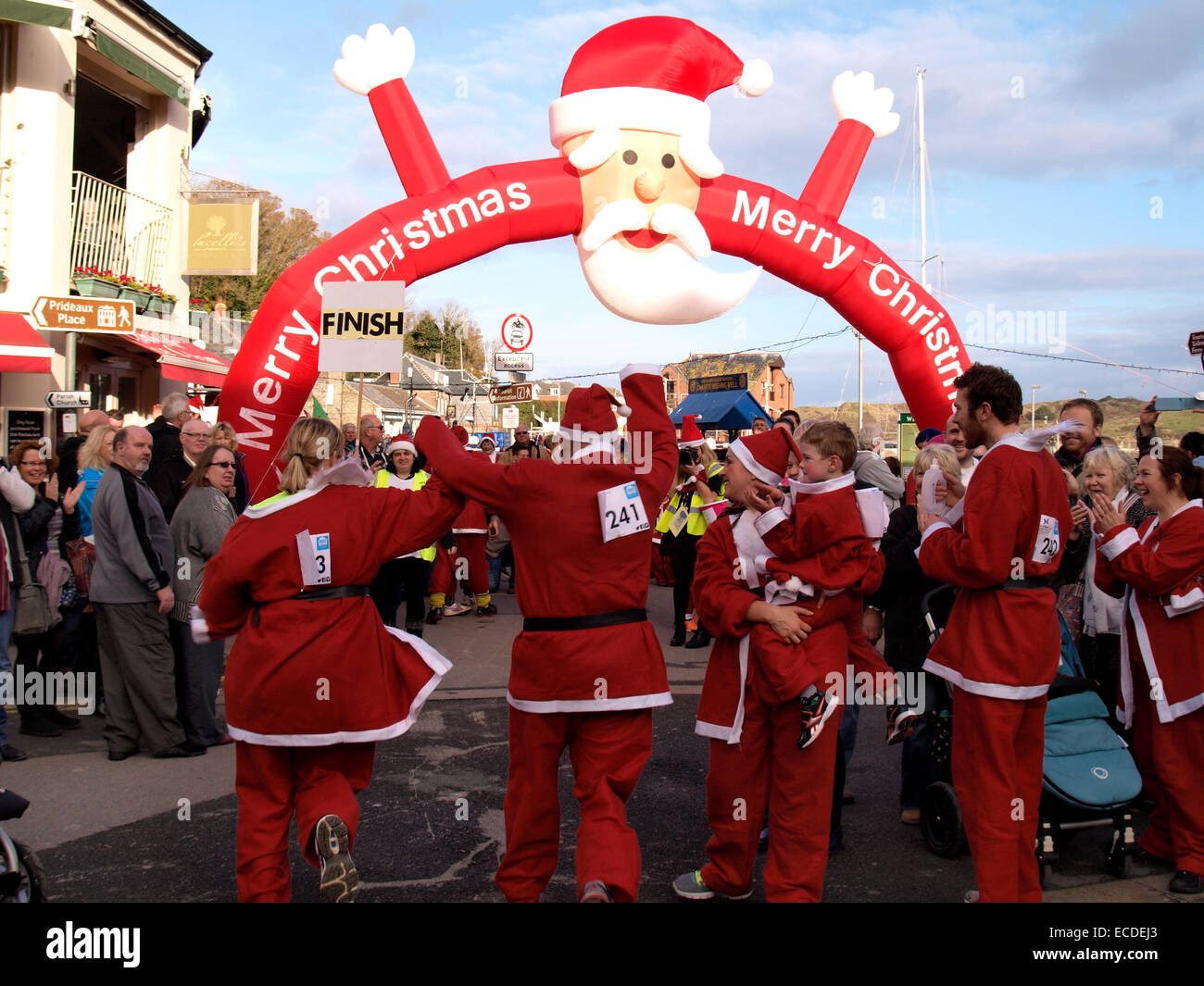 Weihnachtsmänner kommen bis zur Ziellinie auf der Charity-Santa run auf das Weihnachtsfest von Padstow, Cornwall, UK Stockfoto
