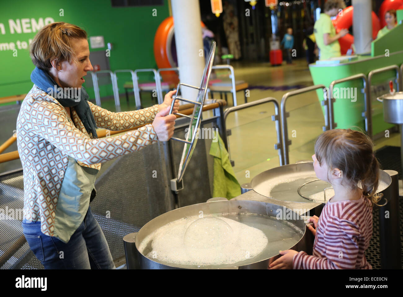 Mutter spielen Bubble-Tochter, die gerade im Science Center Nemo Stockfoto