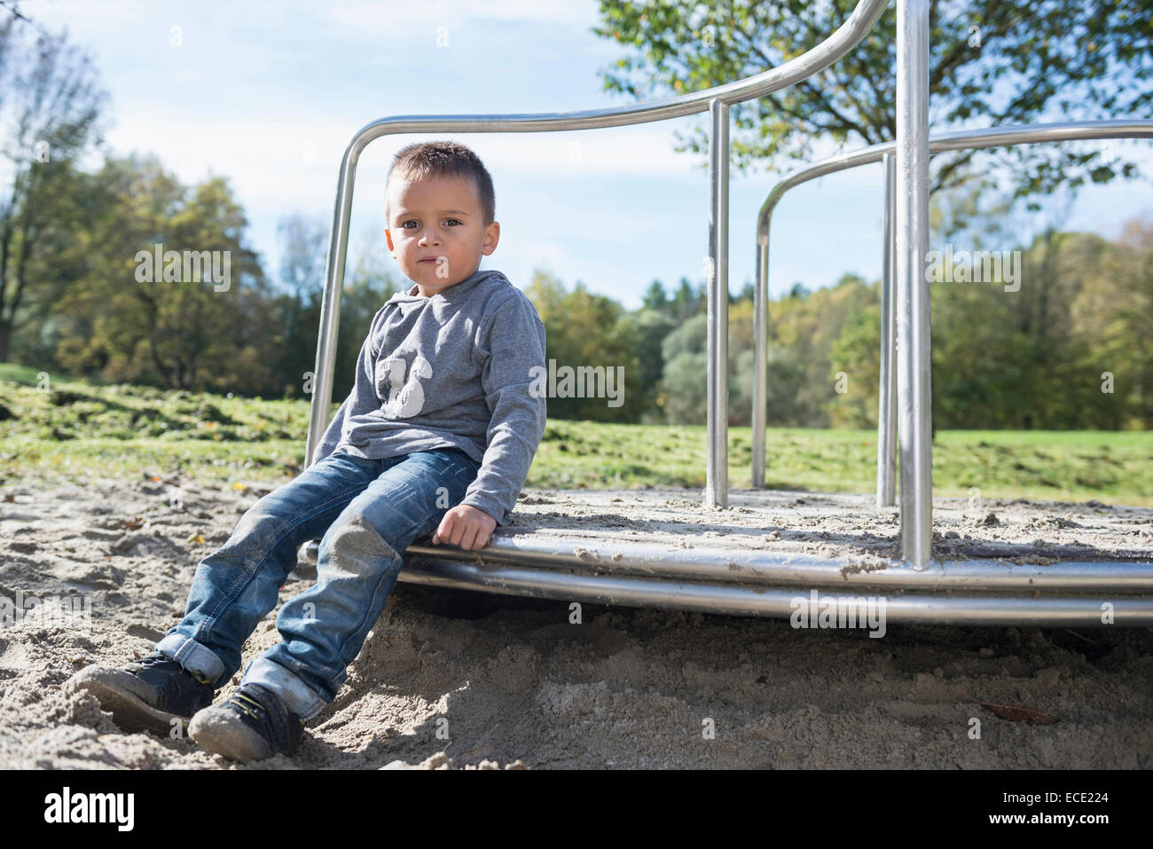 Junge Spielplatz sitzen Porträt Sand Karussell Stockfoto