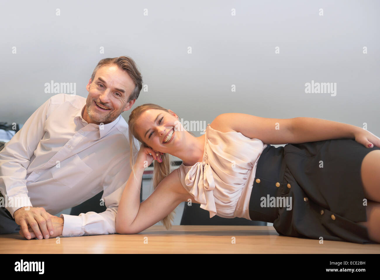 Chef Sekretärin Tisch liegend entspannt lächelnd Stockfoto