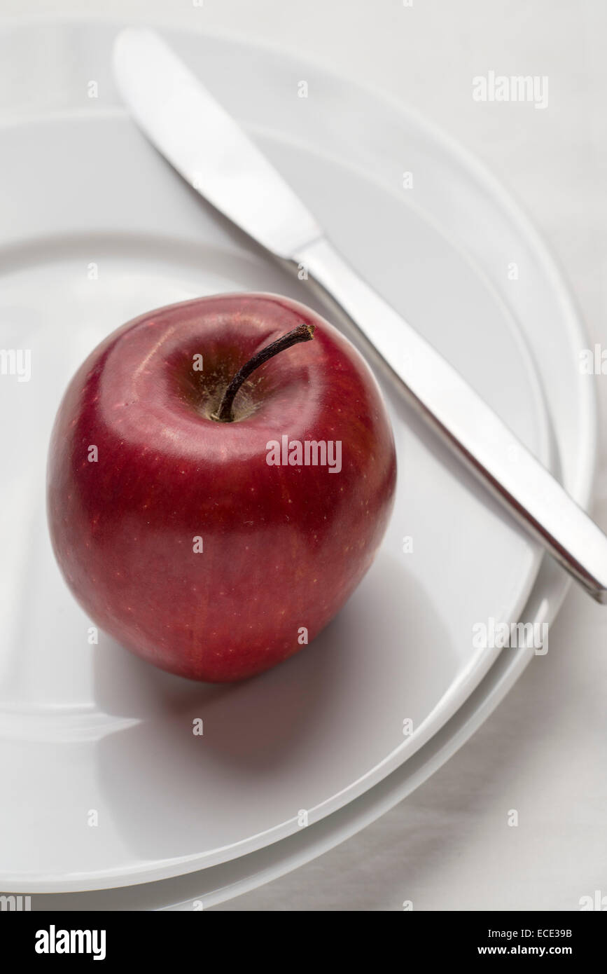 roter Apfel auf Platte und weiße Tischdecke Stockfoto