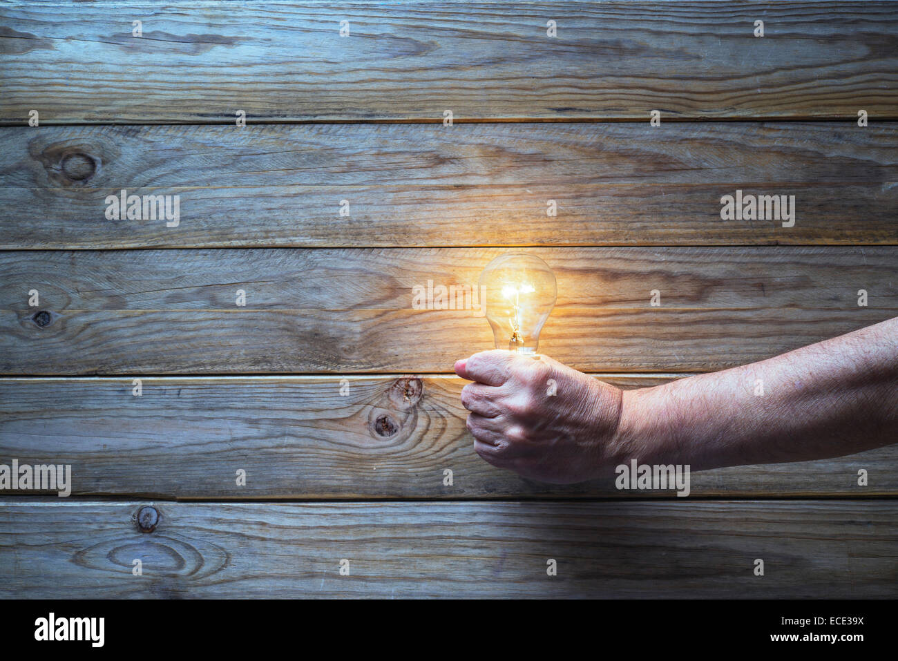 Glühbirne halten in der Hand auf hölzernen Hintergrund Stockfoto