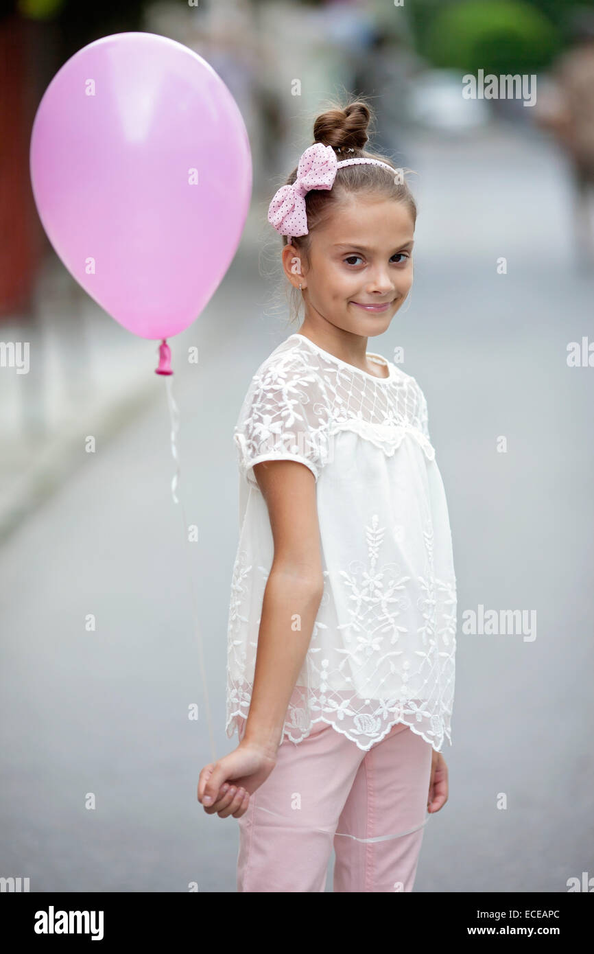 Bulgarien, glückliches Mädchen (8-9) hält Rosa Ballon Stockfoto
