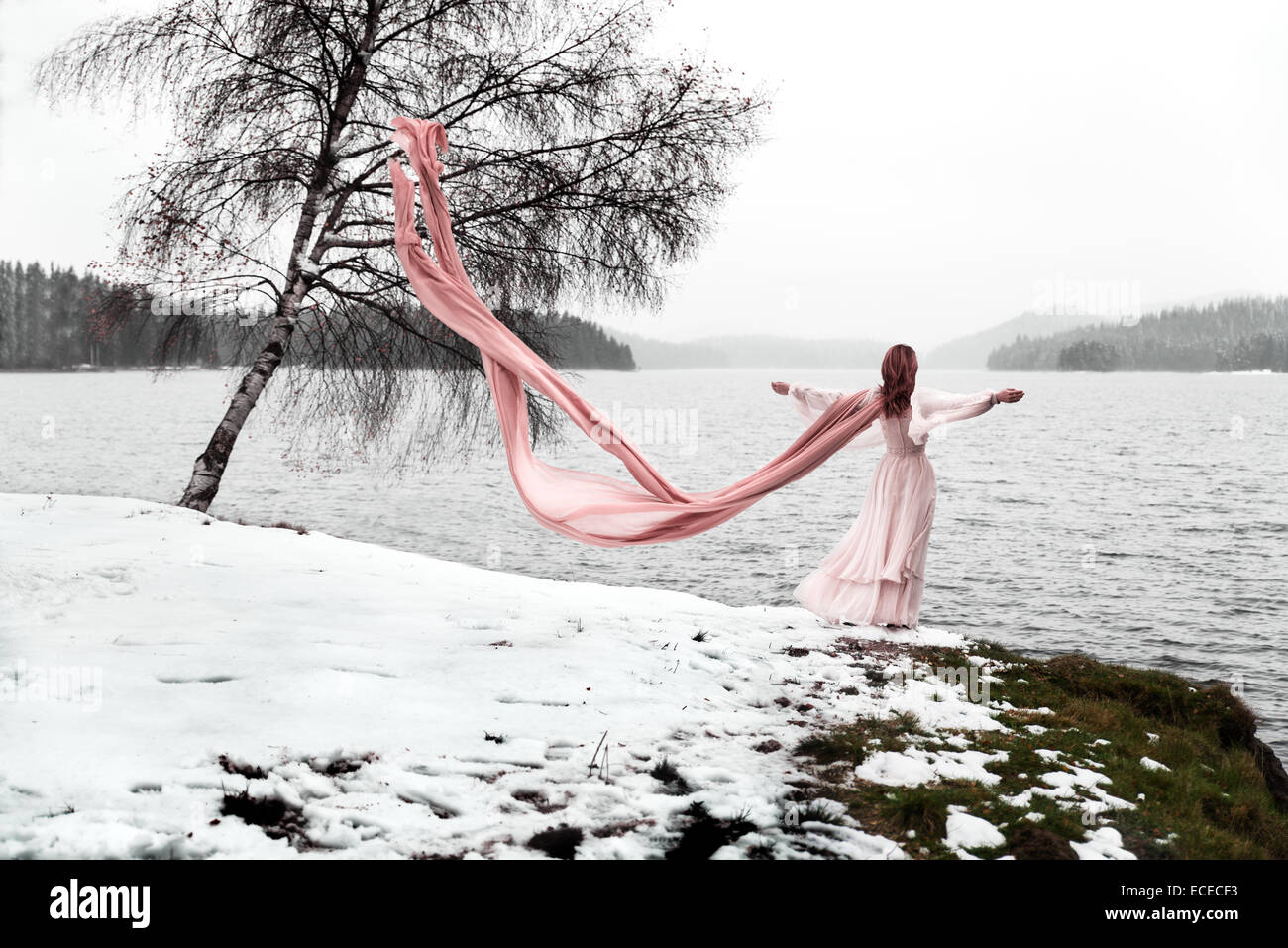 Frau mit langen Schal stehend an einem See im winter Stockfoto