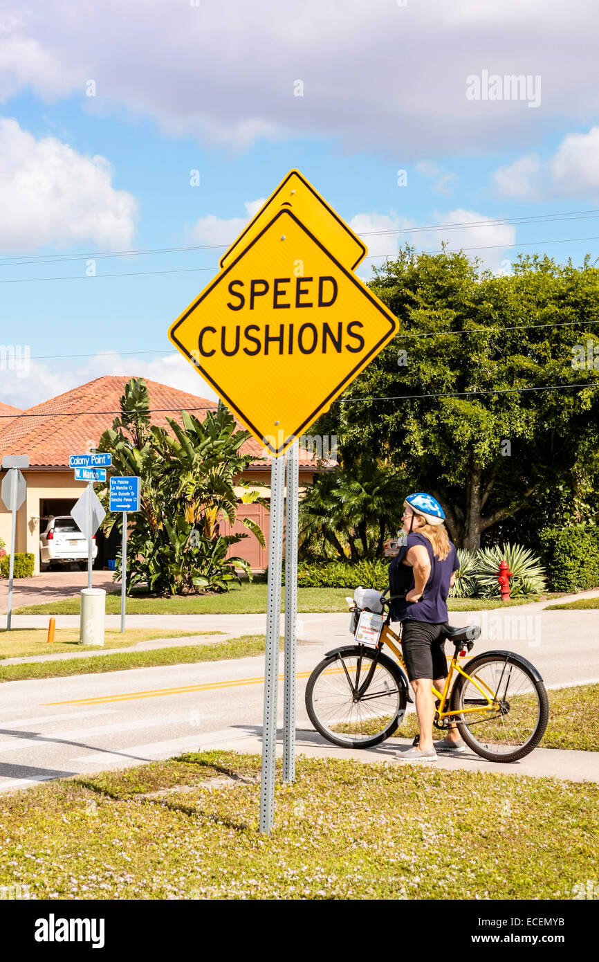 Frau Radfahrer beschlossen, den Bürgersteig zu verwenden, anstatt überqueren die Geschwindigkeit Kissen vor ihr, wie die Zeichen voraussagt. Stockfoto
