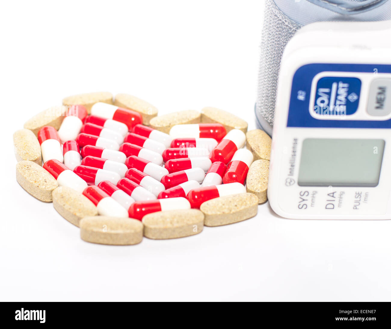 Blutdruckmessgerät und Tabletten in Herzform Anordnung, Symbolfoto von Herz-Kreislauferkrankungen, Diagnose und Medikation Stockfoto