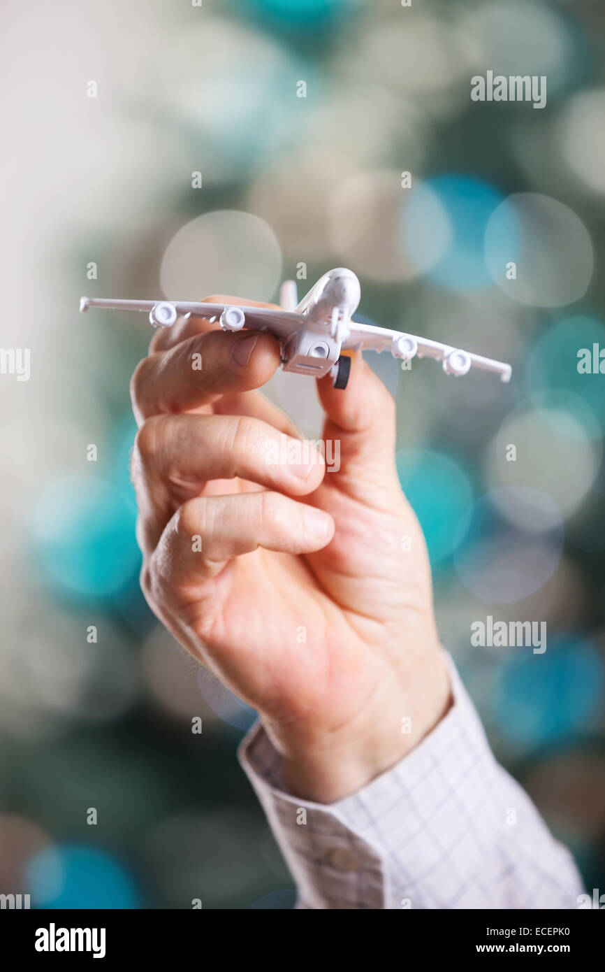 Nahaufnahme des Mannes Hand hält Flugzeugmodell auf Weihnachten Hintergrund Stockfoto