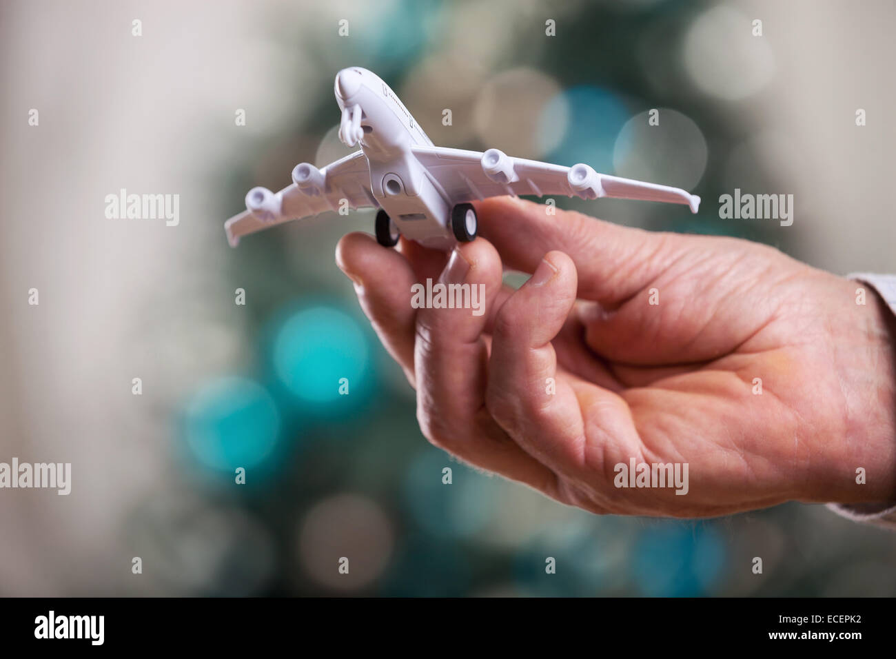 Nahaufnahme des Mannes Hand hält Flugzeugmodell auf Weihnachten Hintergrund Stockfoto