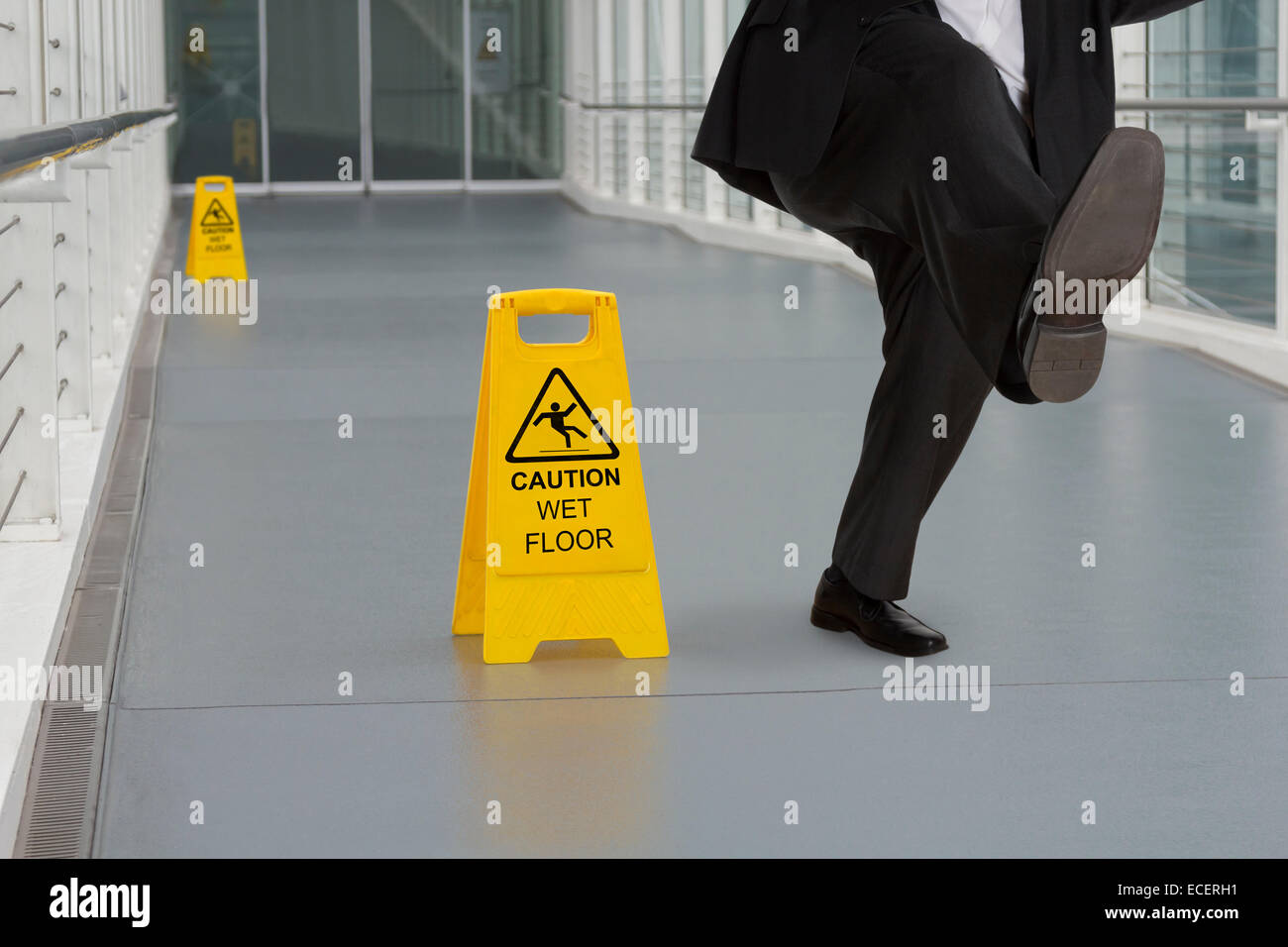 Mann im Anzug ein Ausrutschen auf nassen Boden mit mehreren Warnzeichen Stockfoto