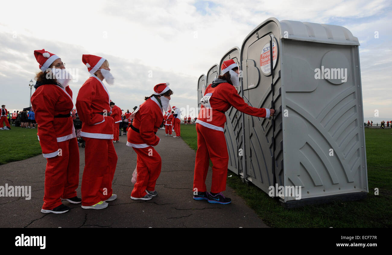 Weibliche Santas in die Warteschlange für die Mobiltoiletten Hunderte an der jährlichen Santa Dash an Hove Strandpromenade Brighton UK 2014 teilnehmen Stockfoto