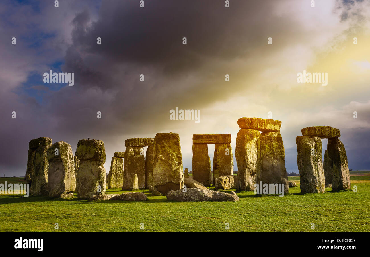 Stonehenge, prähistorische Monument, legen Sie gegen einen düsteren Himmel und eine blaue sonnig bei Amesbury, Wiltshire, UK.hire, Stockfoto