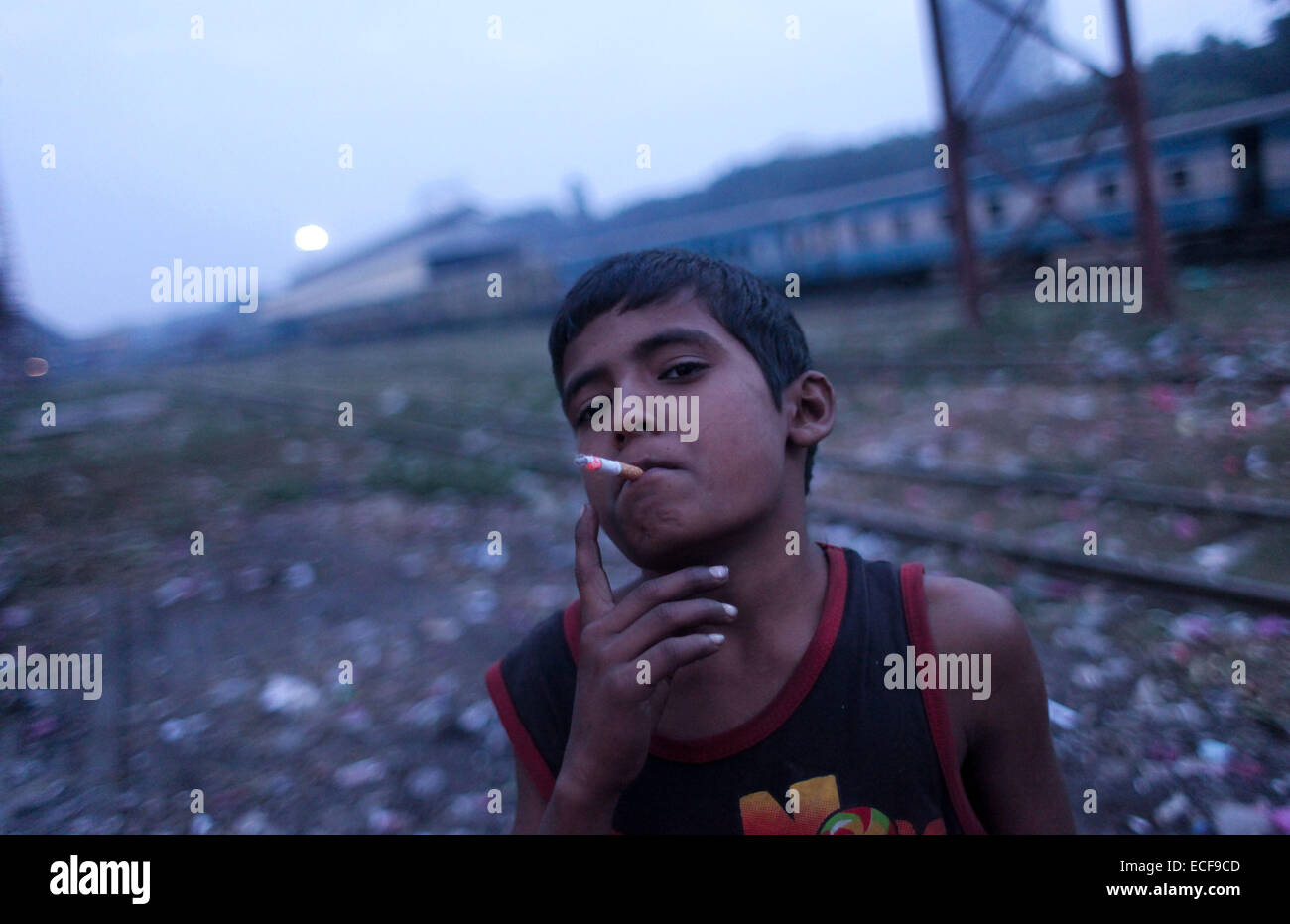 Dhaka, Bangladesch. 13. Dezember 2014. Rana 12. Lebensjahr einen Obdachlosen Straßenhändler ist Rauchen Zigarette in Kamalapur Bahnhof in Dhaka.Cities in Bangladesch sind überfüllt mit dichten Slums, Squattersiedlungen und pavement.dwellings, jedes Haus, Tausende von Kindern. Zunehmende Armut im ländlichen Raum und corresponding.urban Migration weiterhin die Zahl der Menschen in städtischen Slums und auf the.streets anschwellen. Probleme der Arbeitslosigkeit im ländlichen Raum, Landlosigkeit, Flusserosion, Naturkatastrophen, family.conflict und schwache Gesetz und Ordnung Ursache ländlichen Familien zum Verlassen ihrer Heimat auf der Suche nach better.prospects Stockfoto