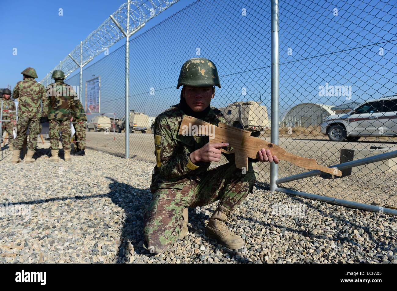 Ein afghanischer Soldat hält eine hölzerne Mock-Gewehr während einer Minenräumung Drill am Camp Shaheen, eine Ausbildungsstätte für Afghan National Army (ANA), befindet sich westlich von Mazar-e Sharif am 13. Dezember 2014. Deutsche Verteidigungsministerin Ursula von der Leyen ist zu einem zweitägigen Besuch in Afghanistan. Foto: JOHN MACDOUGALL/dpa Stockfoto