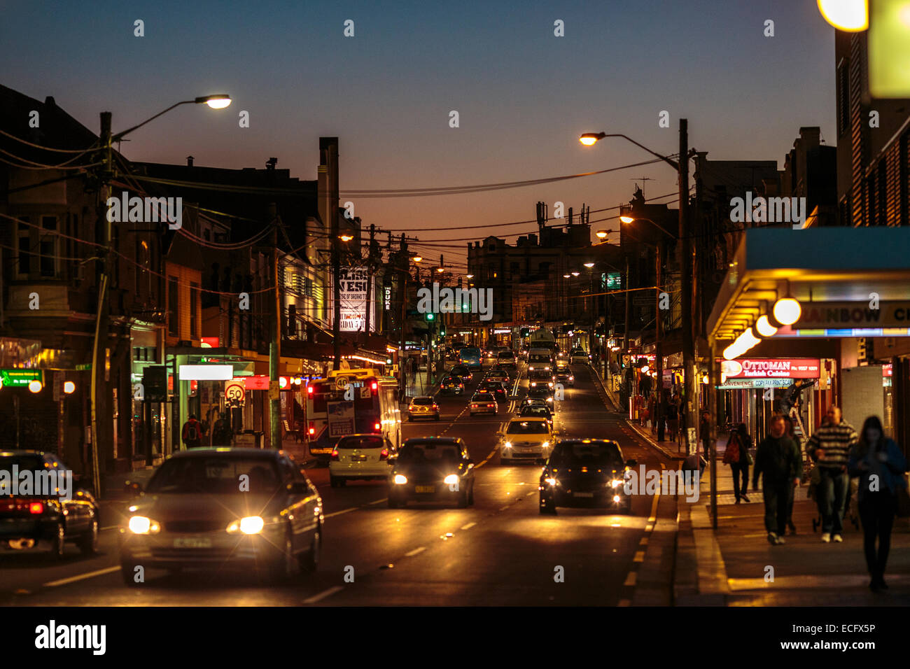 Verkehr saust durch die Straßen von Newtown in Sydney Australia in der Abenddämmerung. Enmore Road verfügt über Restaurants, Cafés und Unterhaltungsmöglichkeiten. Stockfoto