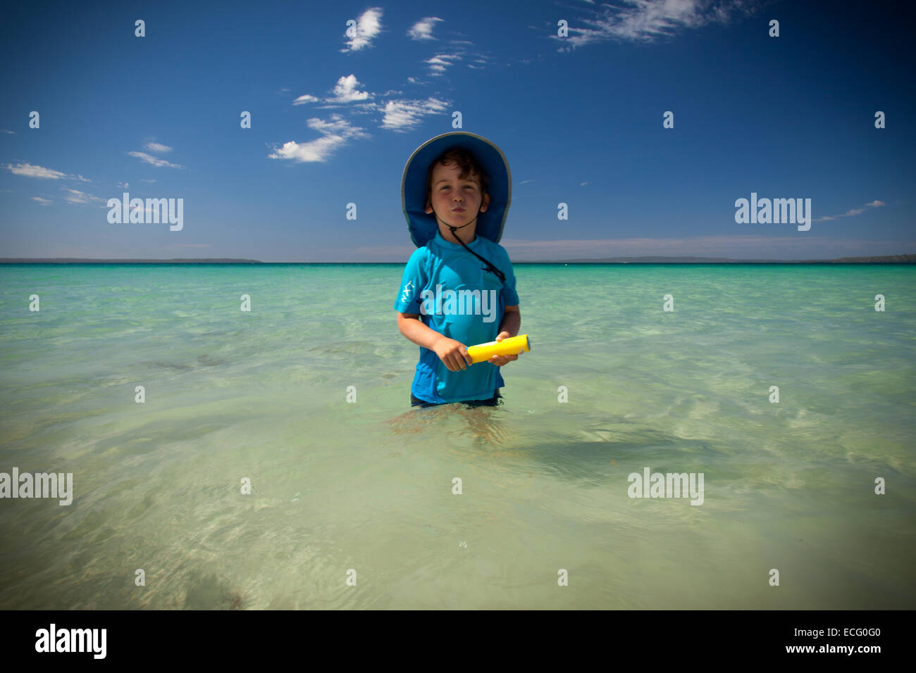 Junge spielt im Ozean mit einer Wasserpistole Stockfoto