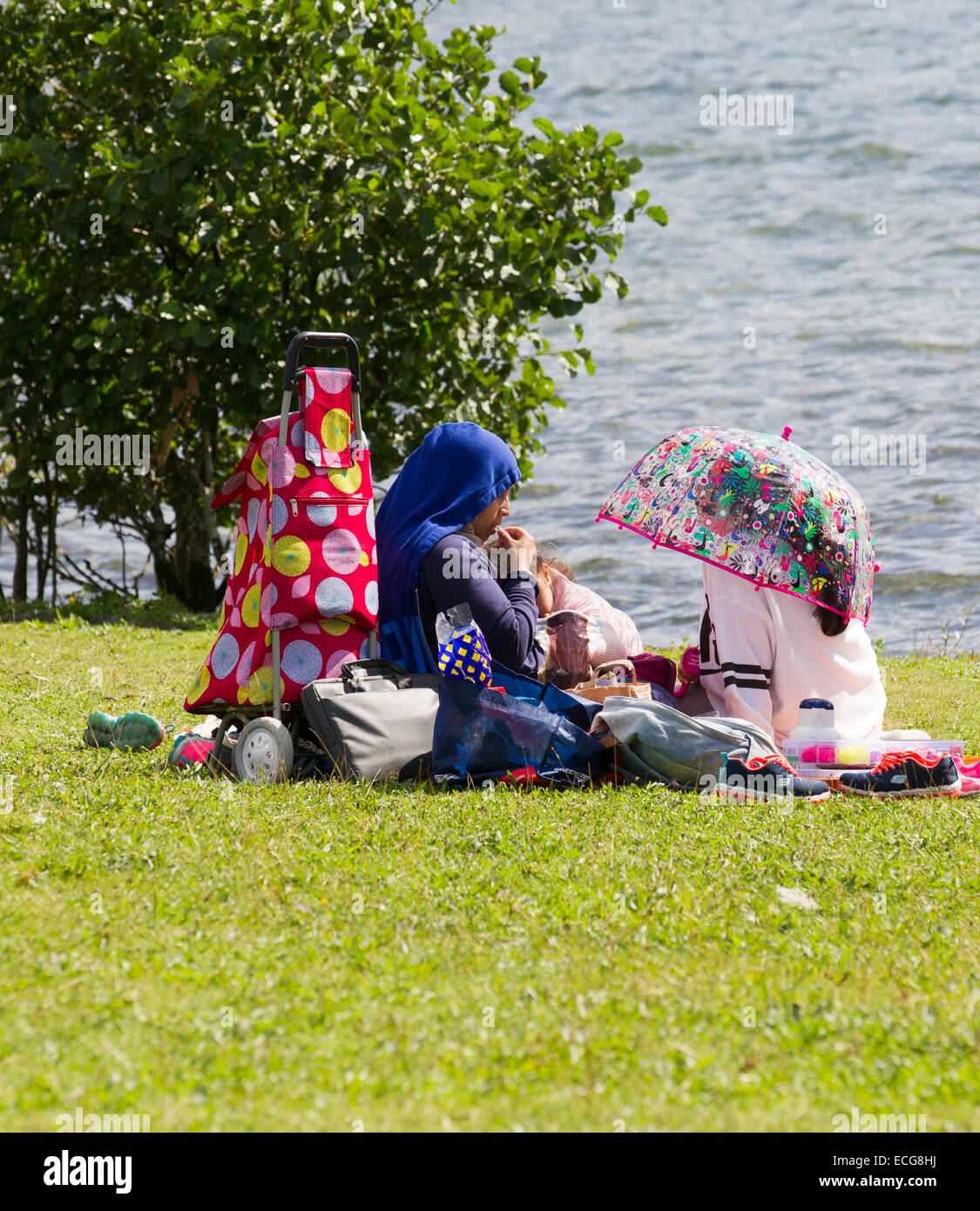 Muslimische Mutter & Tochter sitzen von Lake Windermere Stockfoto
