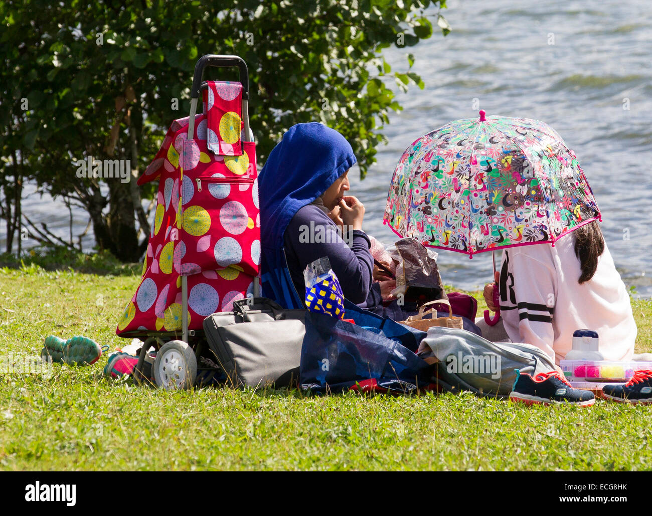 Muslimische Mutter & Tochter sitzen von Lake Windermere Stockfoto