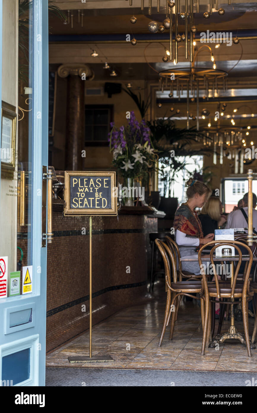 Bitte warten Sie, bis sein sitzenden liest die Zeichen im Grand Cafe auf der High Street, Oxford welche Ansprüche zu den ersten Kaffee Haus i Stockfoto
